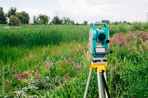 blue surveying   equipment total station on a background of meadow