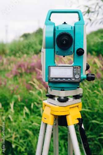 blue surveying equipment total station on a background of meadow