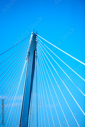 Modern suspension bridge steel ropes against blue sky background