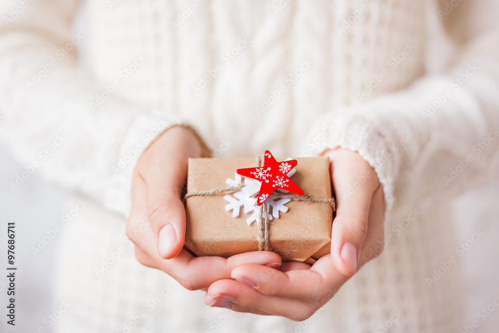 Woman in knitted sweater holding a present. Gift is packed in craft paper with red star. Woman in knitted sweater holding a present. Gift is packed in craft paper with red star.