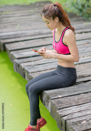 Beautiful sport woman listening to music through headphones on the bridge