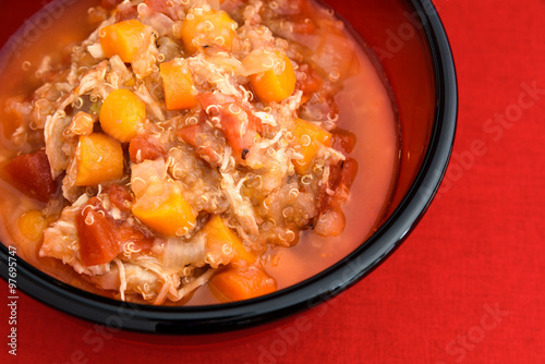 Delicious healthy chicken vegetable soup in a red bowl
