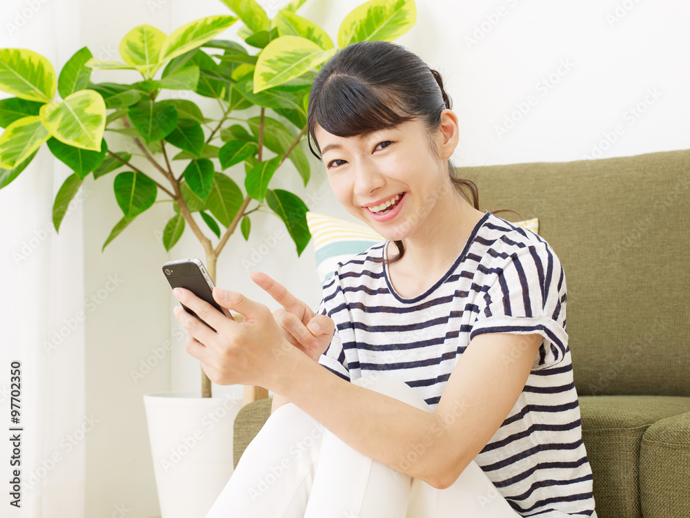 部屋でスマートフォンを使う女性 部屋でスマートフォンを使う女性