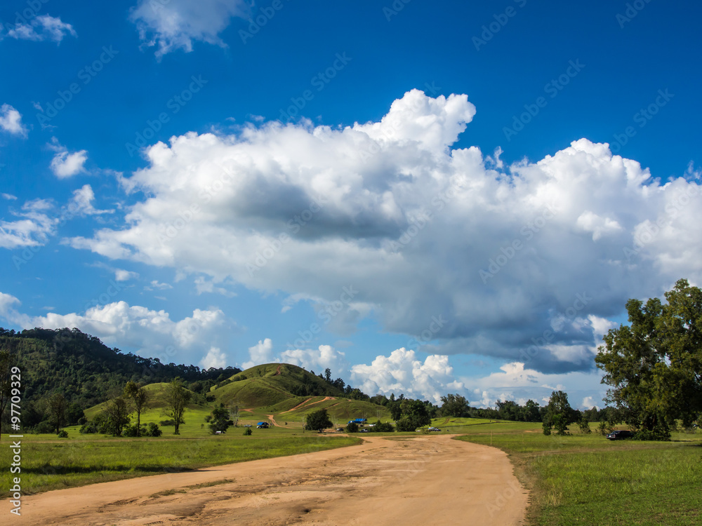 soid road toward  green hill with blue sky