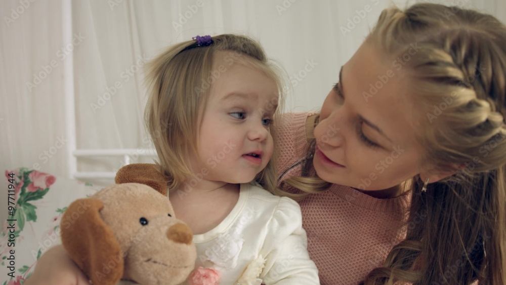 Mother kissing little daughters and their toy Mother kissing little daughters and their toy