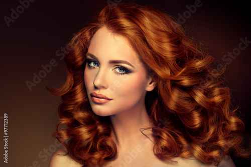 Girl model with long red wavy hair. Big curls on the red head . Hairstyle permanent waving