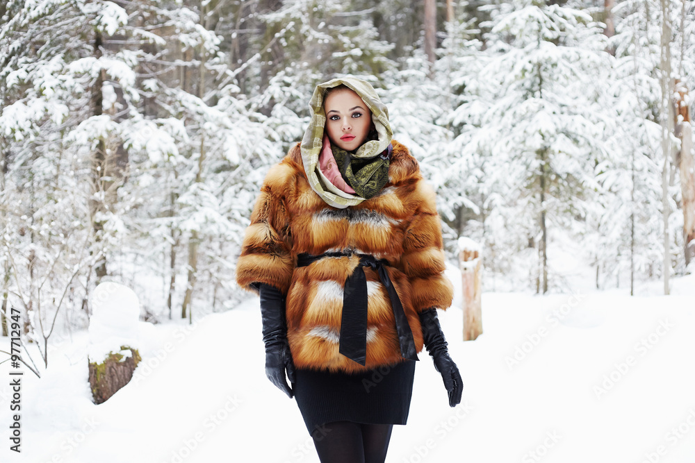 Fototapeta premium winter forest.beautiful young Woman in Fur Coat,leather gloves and scarf