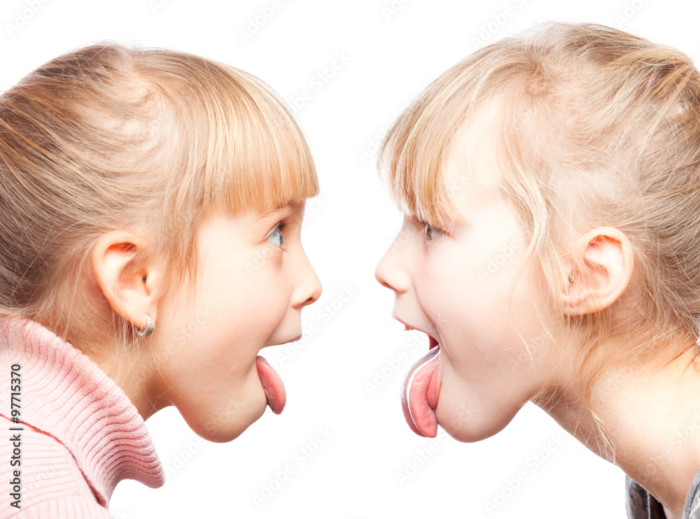 Children sticking out tongues grimacing