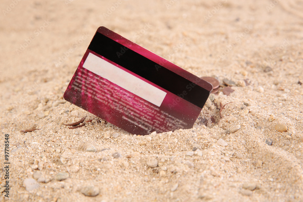credit card in the sand with coins credit card in the sand with coins