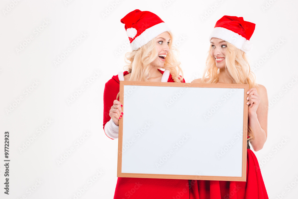 Two sisters holding blank board and looking on each other Two sisters holding blank board and looking on each other