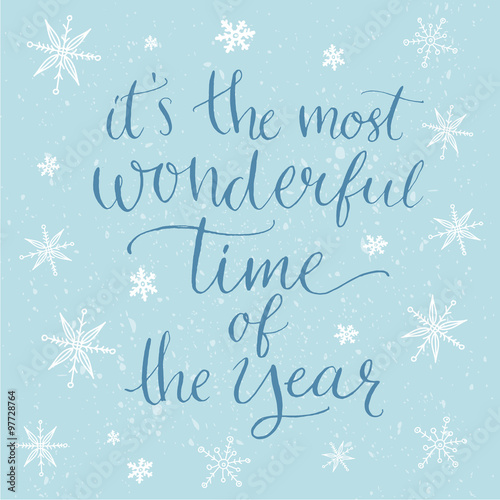 Winter inspirational quote for cards, posters and social media content. It's the most wonderful time of the year. Modern calligraphy at blue background with white snowflakes