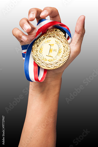 hand holding up a gold medal as a winner in a competition