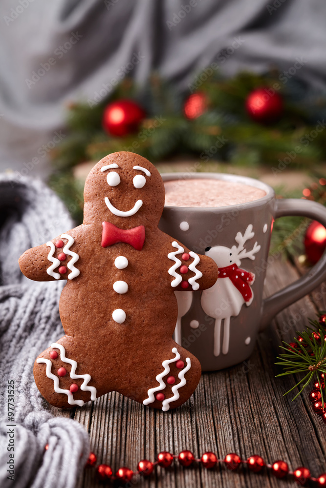 Hot chocolate or cocoa beverage with cinnamon and gingerbread man cookie in new year tree decorations frame on vintage wooden table background. Homemade traditional celebration dessert recipe.