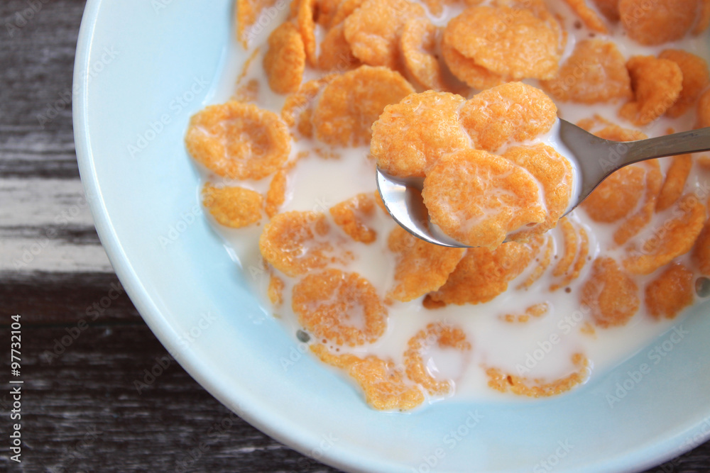 Corn flakes in blue bowl isolated on wood Corn flakes in blue bowl isolated on wood