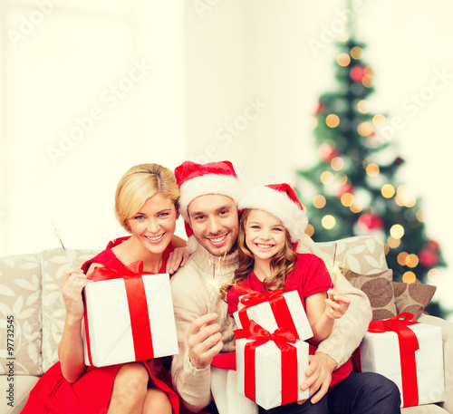 smiling family holding gift boxes and sparkles