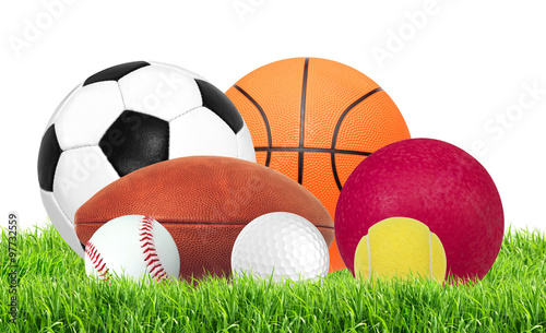 Sports balls in green grass isolated on white
