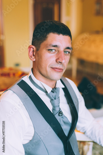 Businessman in a waistcoat and plastron sitting on a chair in the interior Suites