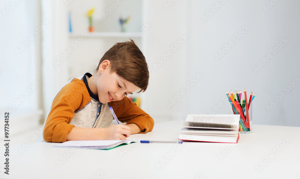 © Syda Productions - smiling student boy writing to notebook at home