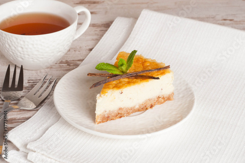 Vanilla cheesecake on a white plate and cup of tea