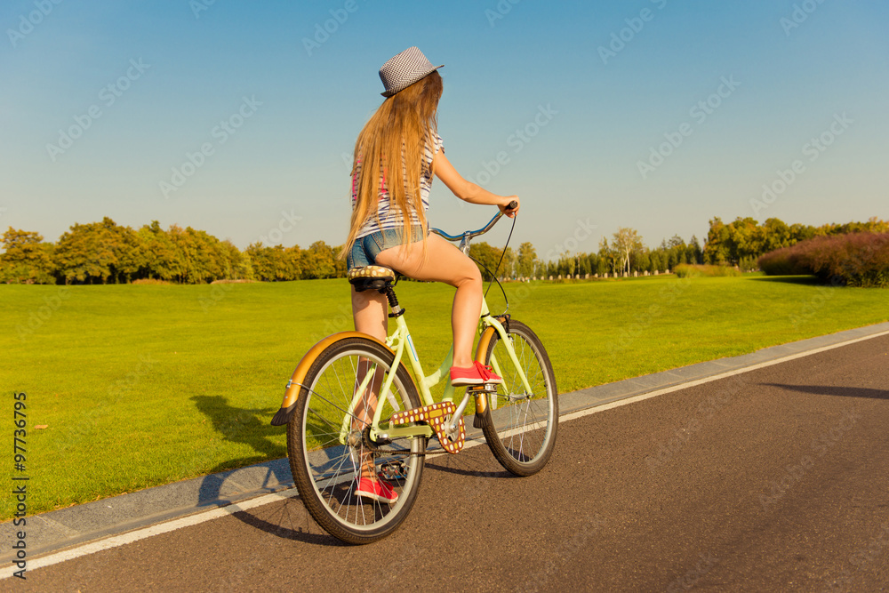 Obraz premium sexy shapely girl with hat and mini shorts ride a bicycle