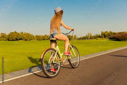 sexy shapely girl with hat and mini shorts ride a bicycle