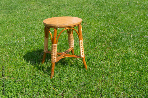 Used handmade wicker stool on a green spring grass