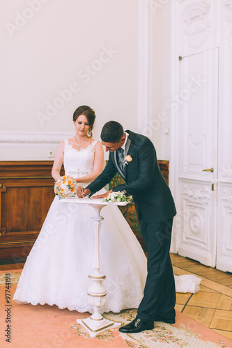 Bride and groom signing marriage license on wedding contract