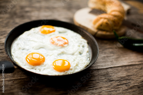 Fried egg in a frying pan on a wooden table