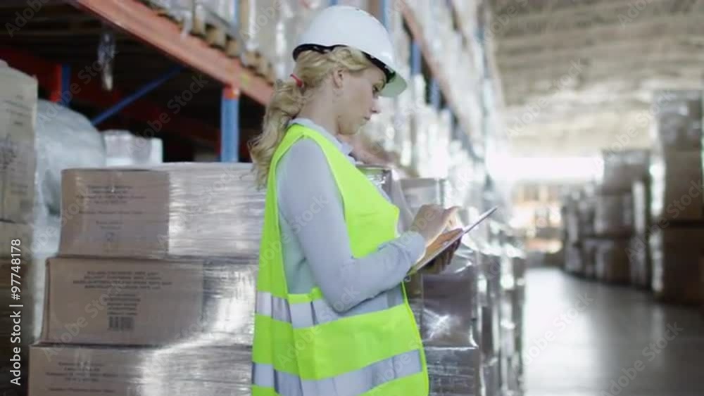 Woman Worker in Hard Hat Working on Tablet in Logistic Warehouse. Shot on RED Cinema Camera. Woman Worker in Hard Hat Working on Tablet in Logistic Warehouse. Shot on RED Cinema Camera.