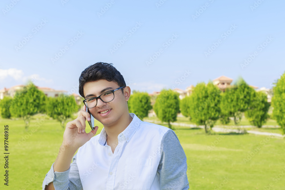 Happy smiling young man talking on mobile outdoor.
