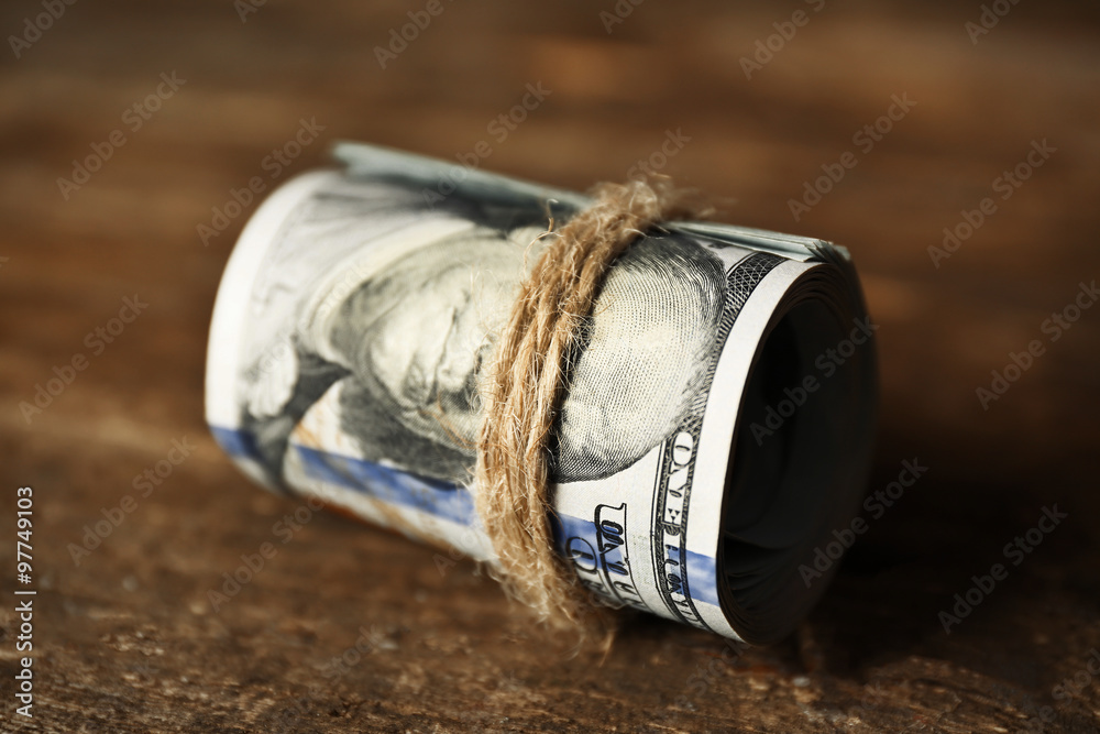 Fototapeta premium Dollars roll on wooden background