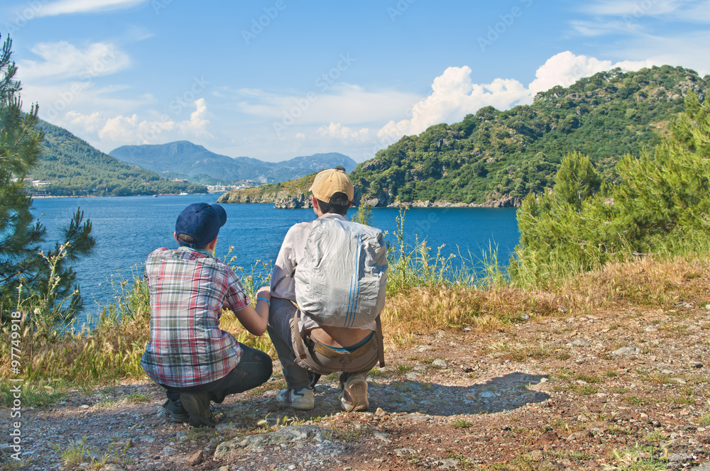 teenage son with his father looking at sea view