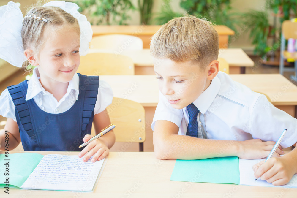 Students or classmates in school classroom sitting together at desk Students or classmates in school classroom sitting together at desk