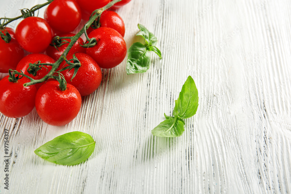 Cherry tomatoes with basil on wooden table close up Cherry tomatoes with basil on wooden table close up