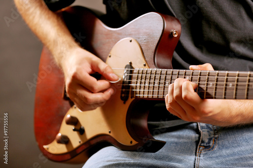 Young musician playing electric guitar close up