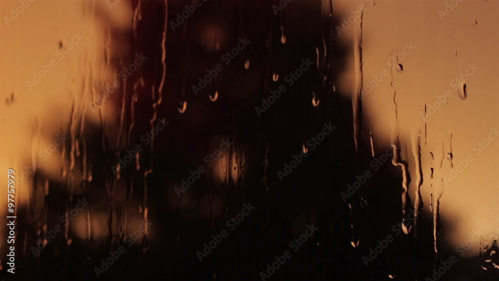 Closeup of fall rain on a window pane dark orange background