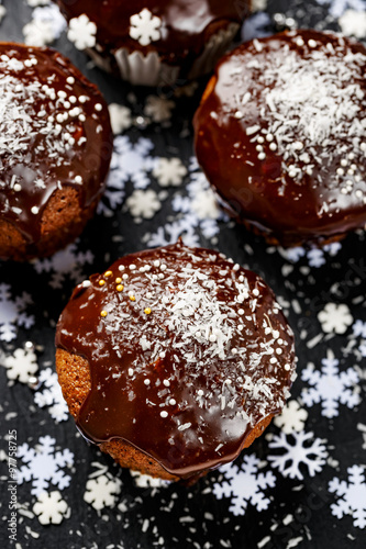 Chocolate muffins sprinkled with coconut flakes on a dark background