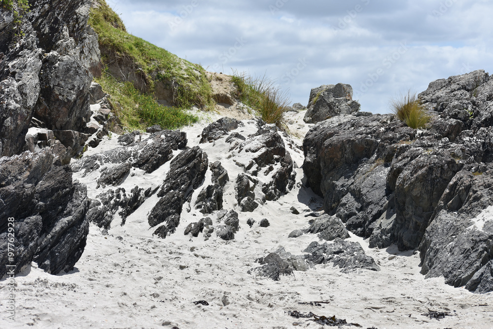 End of a beach with sand on the rocks found there.