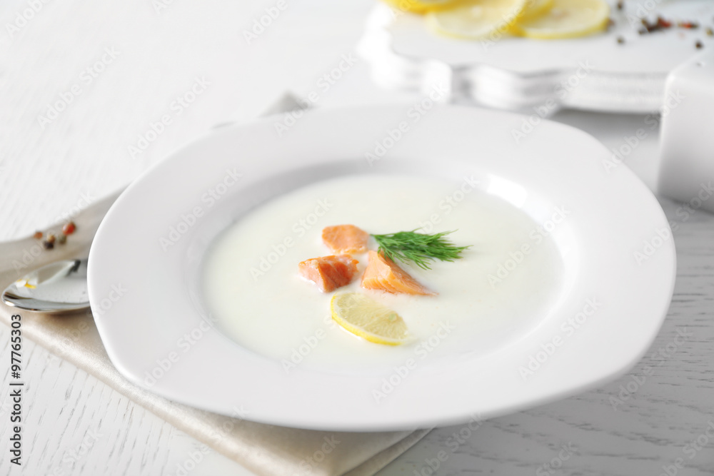 Delicious cream soup with fish and sliced lemon on white table in the restaurant Delicious cream soup with fish and sliced lemon on white table in the restaurant