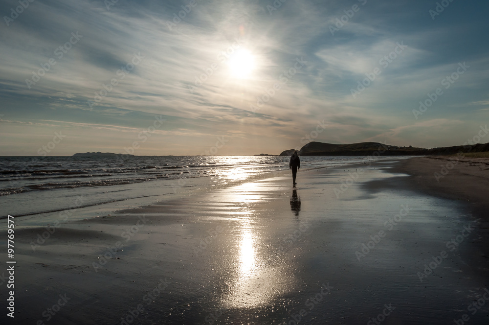  a man walking at the beach at sunrise