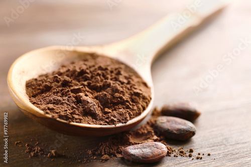 Wooden spoon with cocoa powder on the table, close-up