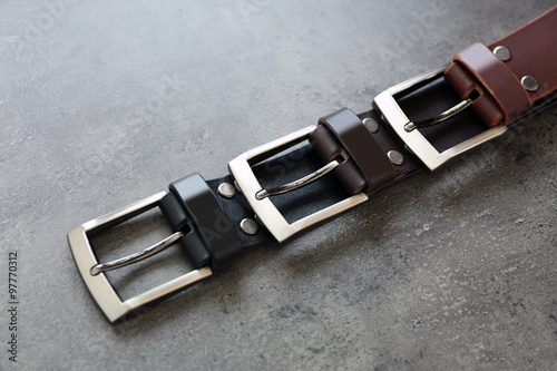 Leather belts with buckles on gray background