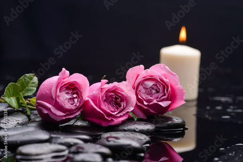 Lying down rose with petals and candle with therapy stones 