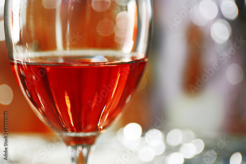 A glass of pink wine on blurred lighted background