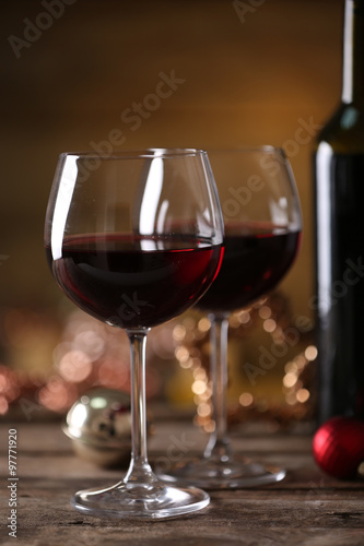 Red wine and Christmas ornaments on wooden table on wooden background