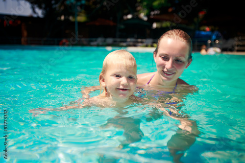 closeup mother teaches small daughter swim smile in azure pool