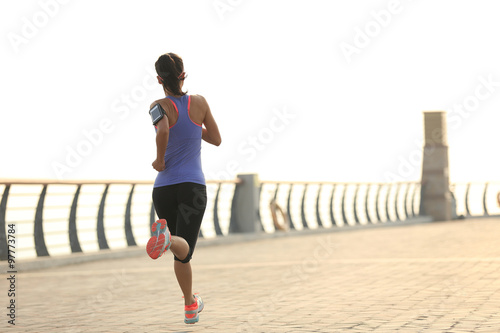 young woman runner athlete running at seaside