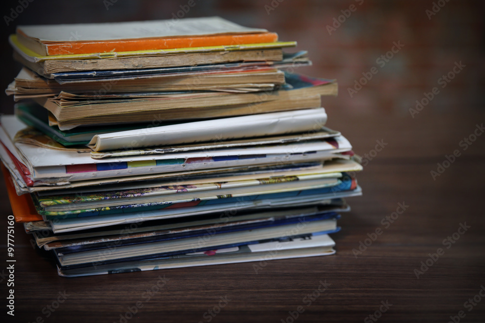 Pile of old books on wooden table against brick wall, close up Pile of old books on wooden table against brick wall, close up