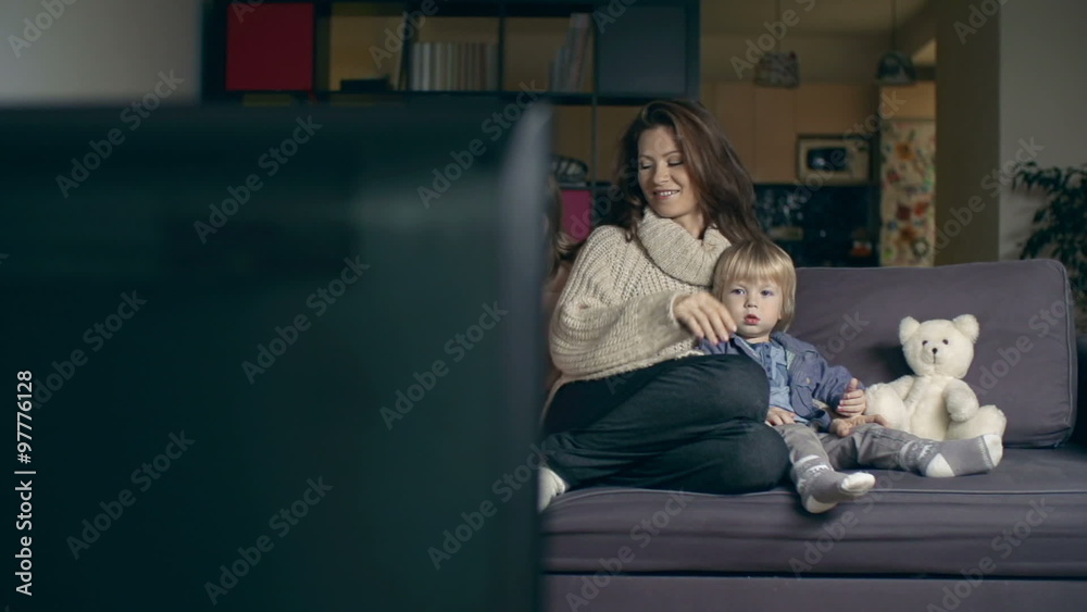 Beautiful mother watching family movie together with her little son and daughter Beautiful mother watching family movie together with her little son and daughter