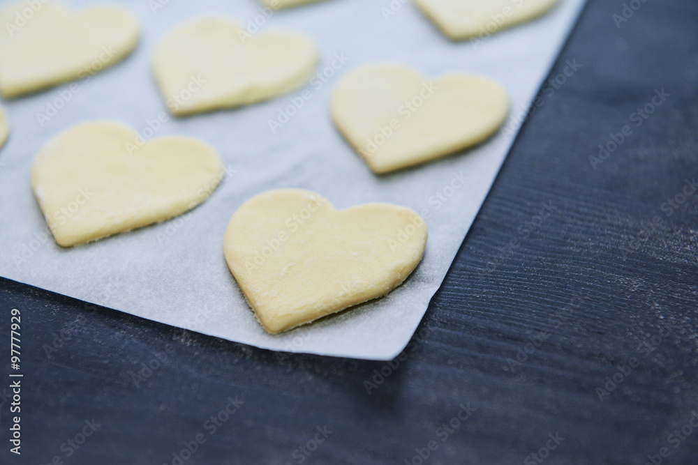 Uncooked heart shaped biscuits on a baking paper
